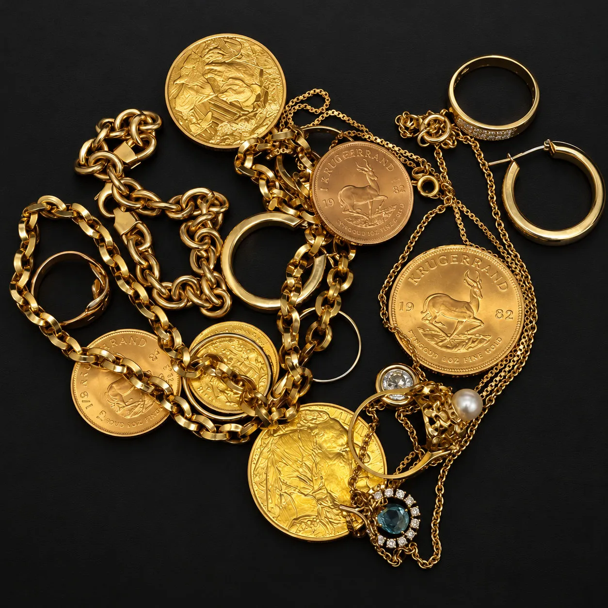 Goldketten, Ringe, Ohrringe und Krügerrand-Münzen auf schwarzem Grund