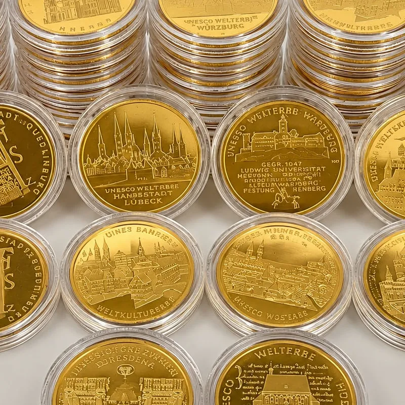 Goldene Gedenkmünzen mit UNESCO-Welterbe-Motiven in Sammlerkapseln