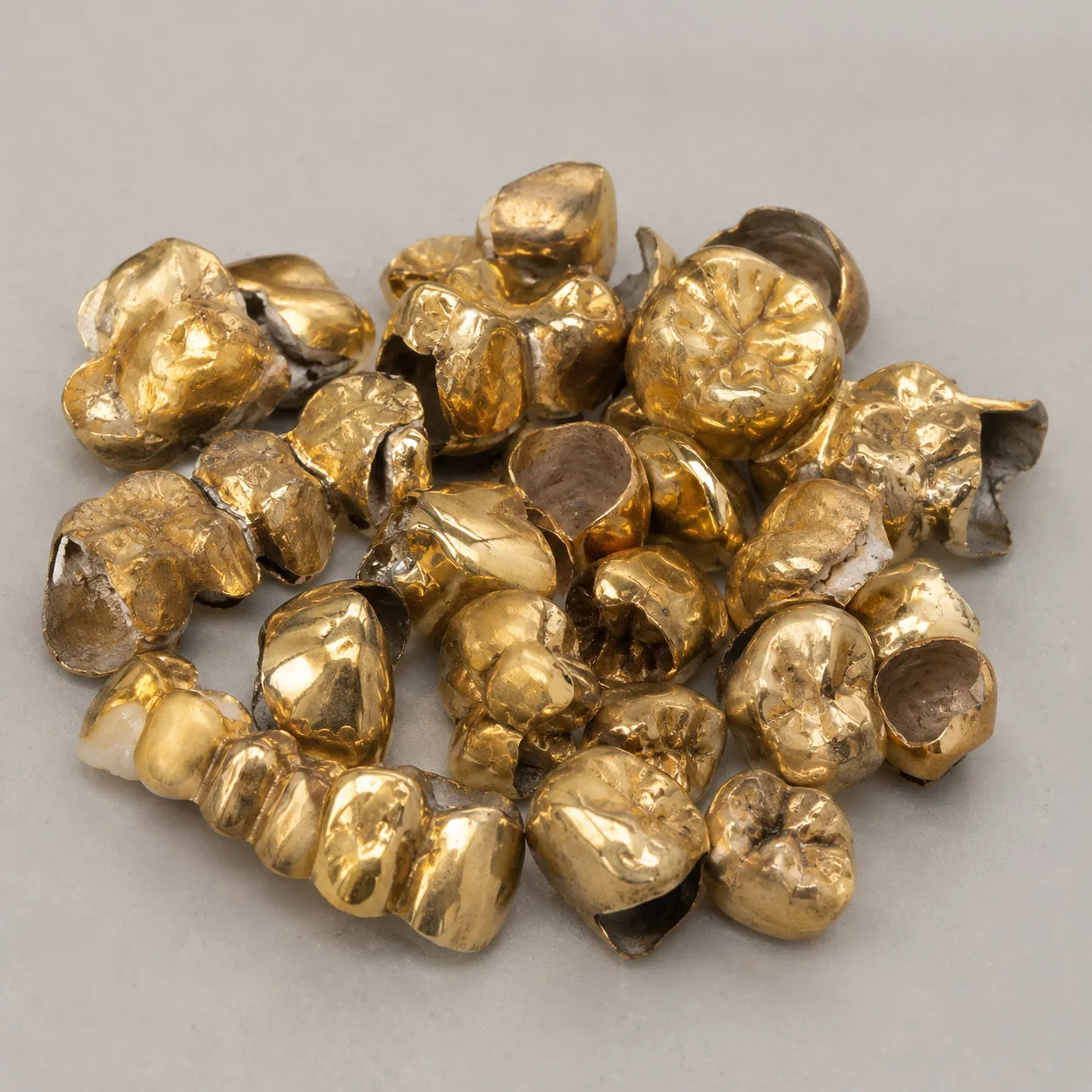Haufen goldener Zahnkronen auf grauem Grund
